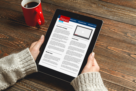 Person holding tablet reading articles